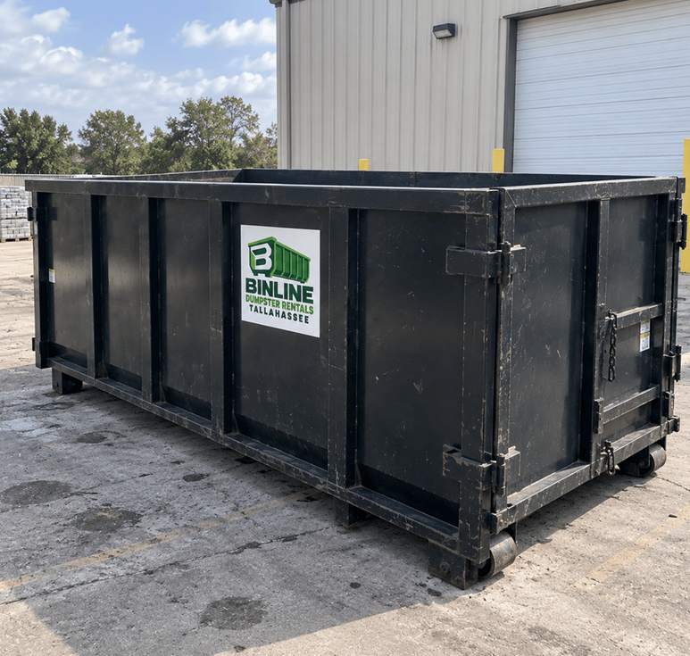 Black steel roll-off dumpster on rollers with the Binline Dumpster Rentals Tallahassee logo on the side panel