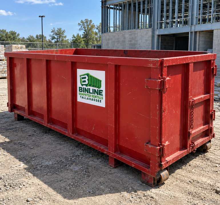 Red Binline Dumpster Rentals Tallahassee roll-off dumpster set down on gravel at a building site with steel framing behind it